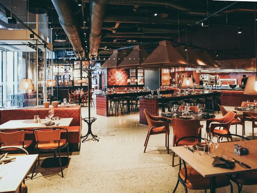 Ambiente de restaurante con mesas y cocina abierta